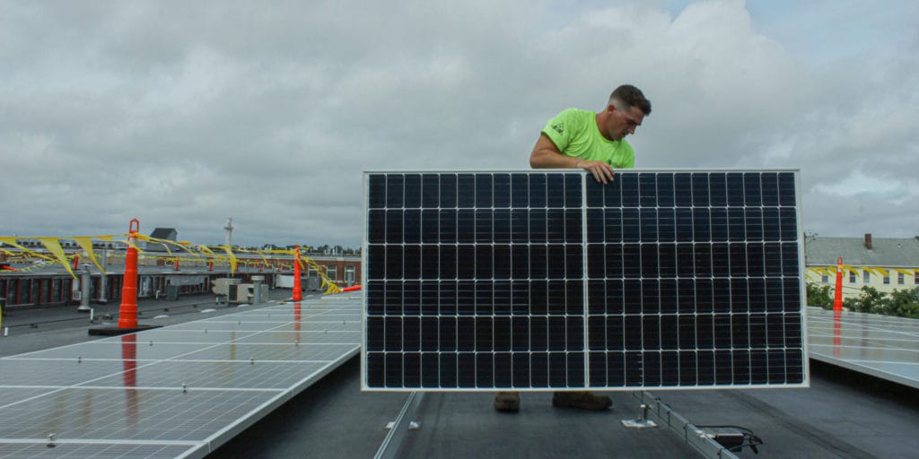 Worker installing a rooftop solar panel