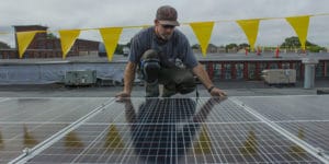 Man installing a solar panel on a rooftop.