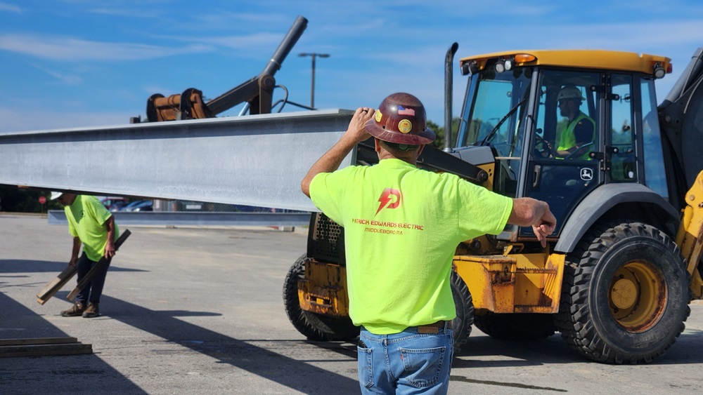 Construction workers guide large steel I-beam