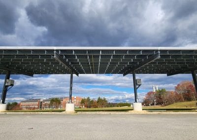A solar carport - built by MA solar construction company overlooks a grassy field
