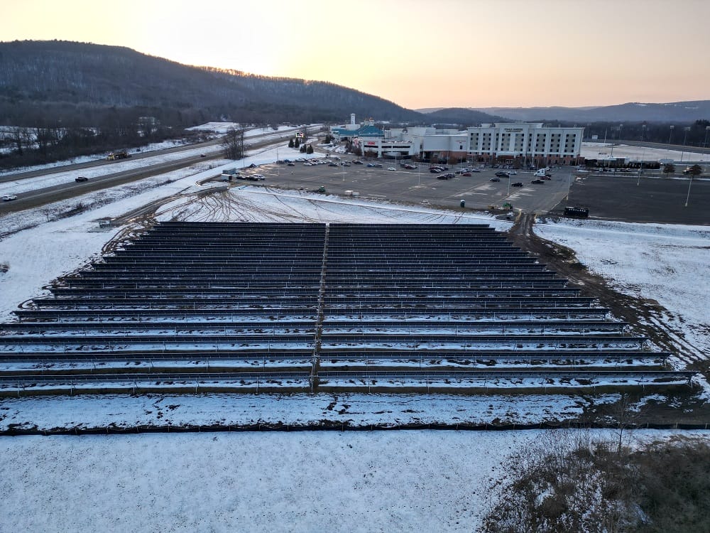 Picture shows a few acres of solar power arrays, mounted on a land lease for solar farm, some snow on the ground