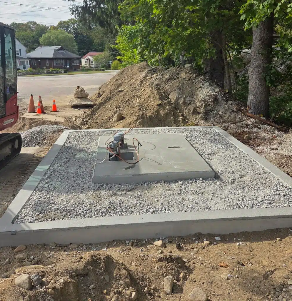 Utility transformer pad prepared with gravel, rebar, and concrete layers for solar project inspections and approvals during commercial construction.