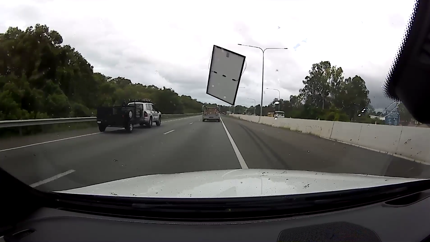 This photograph shows a solar panel flying through the air after blowing off a truck on the highway.