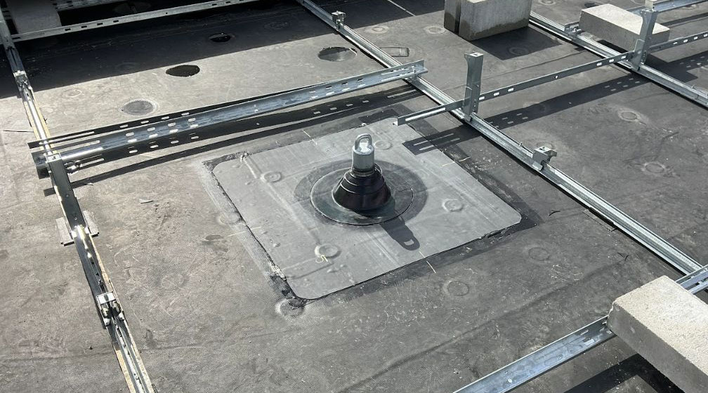 A permanent safety tie-off anchor on a commercial EPDM rooftop with a new solar installation