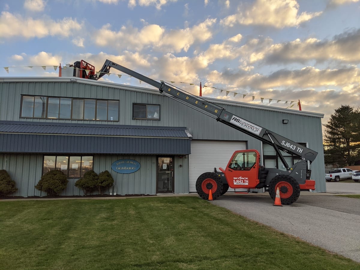 Telescopic boom lift raises pallets of panels to the roof 