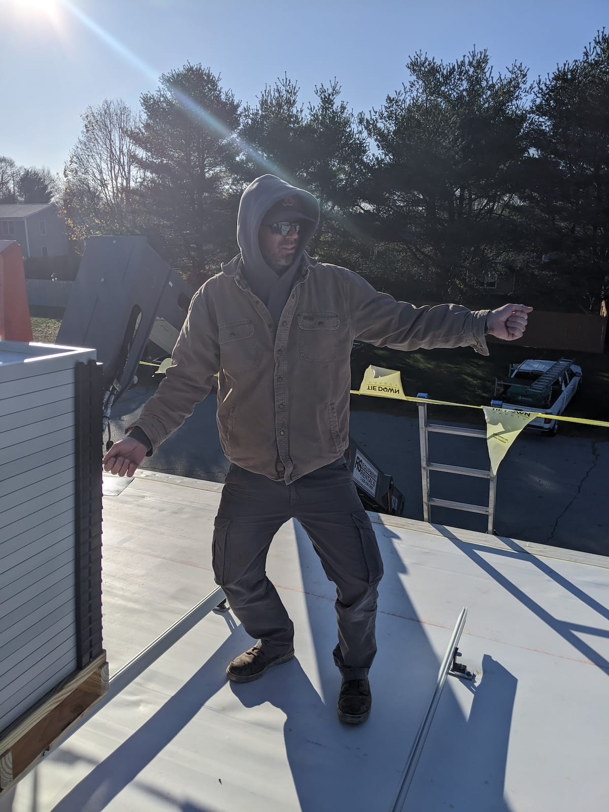 Solar installer on white TPO roof with ladder and pallet of solar panels