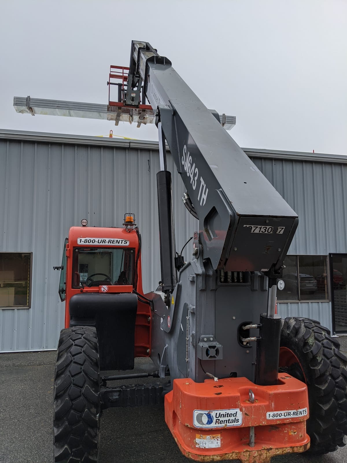 Boom lift raising workers and solar panels to roof