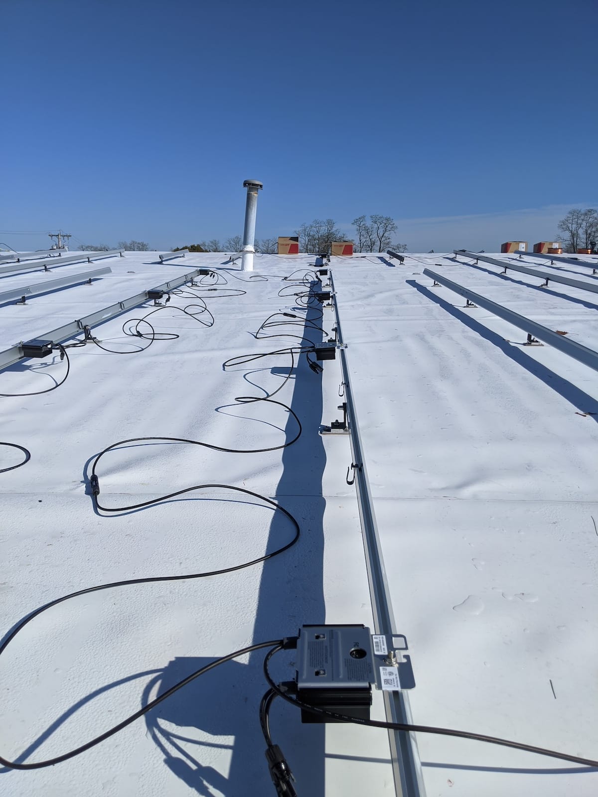 Optimizers connected to Ironridge extruded rail for mounting solar panels on roof